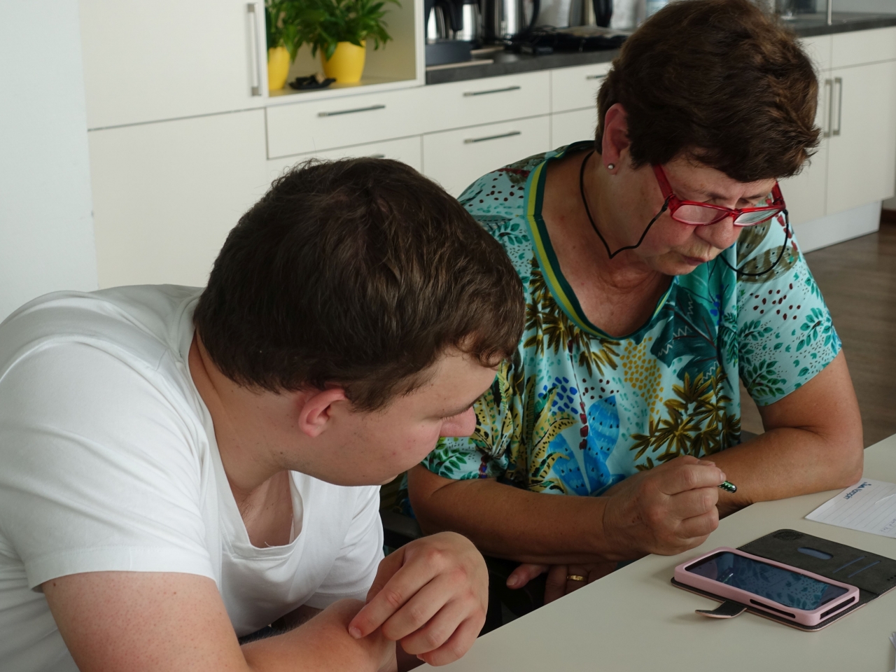 Ein Smartphone Pate und eine ältere Dame schauen auf ein Smartphone.