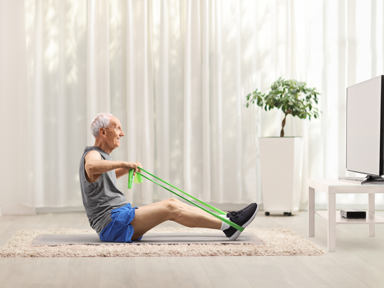 Älterer Mann macht Sport vor dem Fernseher