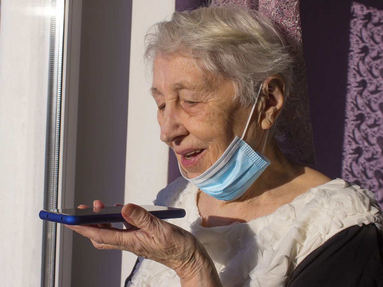 Ältere Frau spricht in ein Smartphone